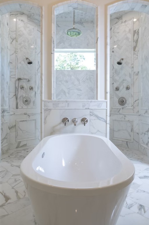 Luxury master bathroom walk-in shower featuring floor-to-ceiling marble tile, a frameless glass enclosure, and a built-in stone bench.