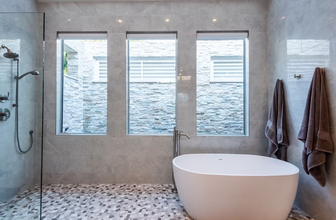 Luxury bathroom vanity featuring white cabinetry, a thick marble countertop, and large rectangular mirrors with contemporary vanity lighting.