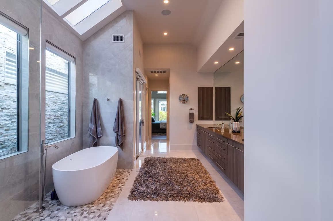 Luxury master bathroom featuring a freestanding white soaking tub, marble-tiled walls, and a large walk-in glass shower.