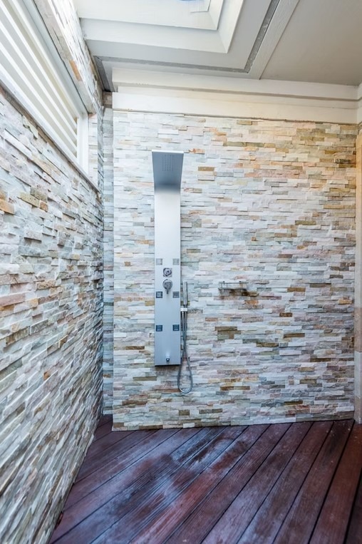 Luxury master bathroom featuring a freestanding white soaking tub, floor-to-ceiling marble tile, and a spacious glass-enclosed shower.