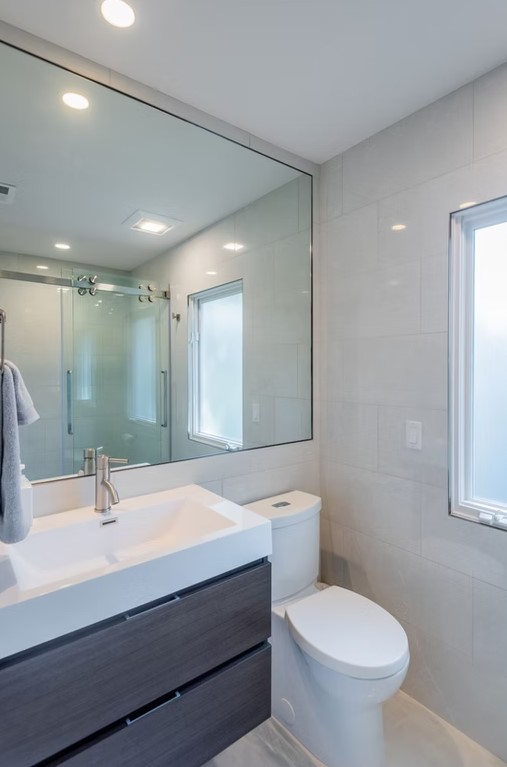 Luxury master bathroom walk-in shower with floor-to-ceiling marble tile, a frameless glass door, and polished chrome hardware.