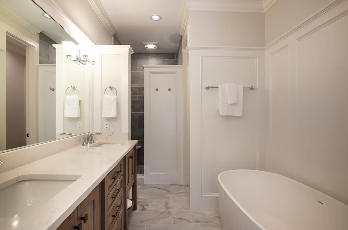 Luxury master bathroom corner featuring a freestanding white soaking tub, floor-to-ceiling marble tile, and a spacious glass-enclosed shower.
