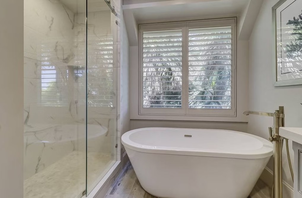 Luxury master bathroom featuring a spacious walk-in shower with frameless glass, marble-tiled walls, and a built-in stone bench.