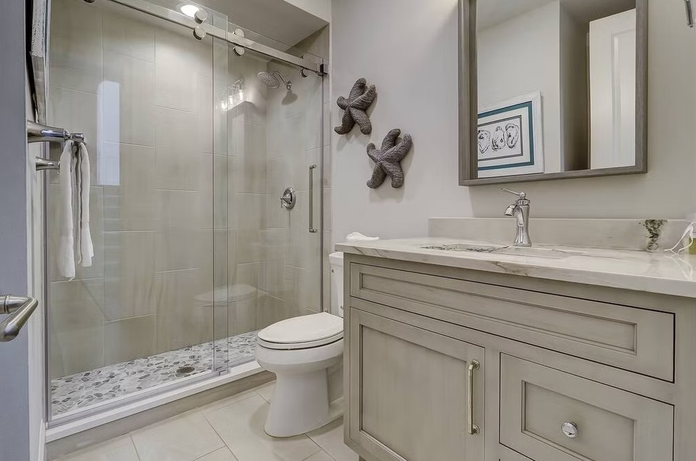 Luxury master bathroom featuring a white freestanding soaking tub, marble-tiled walls, and an expansive walk-in glass shower.