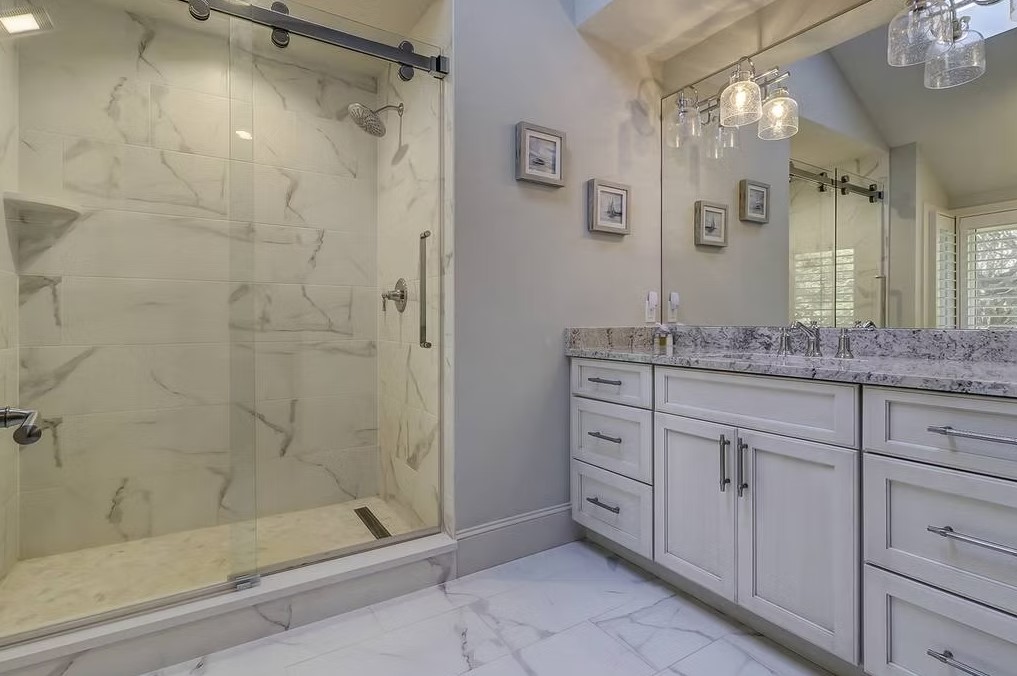 Luxury master bathroom featuring a spacious walk-in shower with frameless glass, marble-tiled walls, and a built-in stone bench.