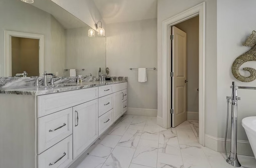 High-end bathroom vanity featuring dual sinks, custom white cabinetry, and a thick marble countertop with elegant grey veining.