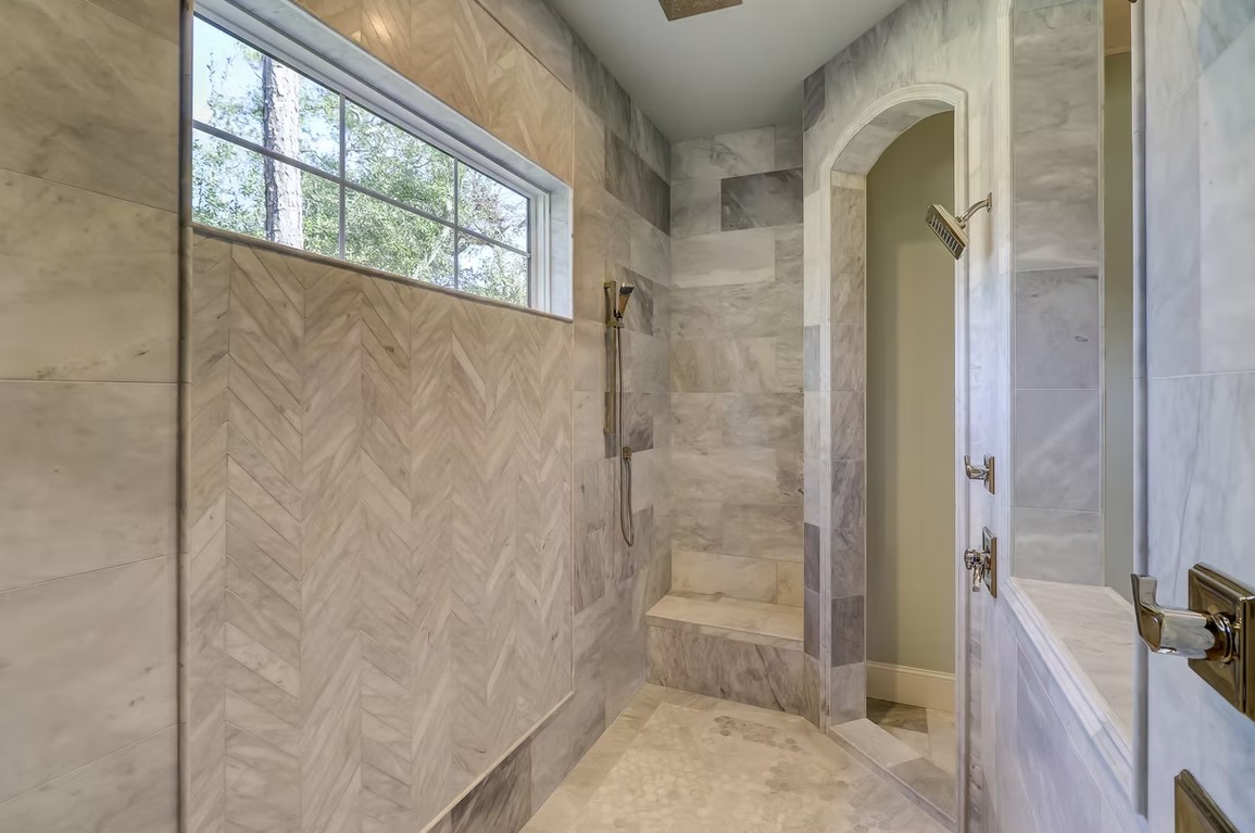 Luxury bathroom vanity featuring white cabinetry, a thick marble countertop, and large rectangular mirrors with contemporary vanity lighting.