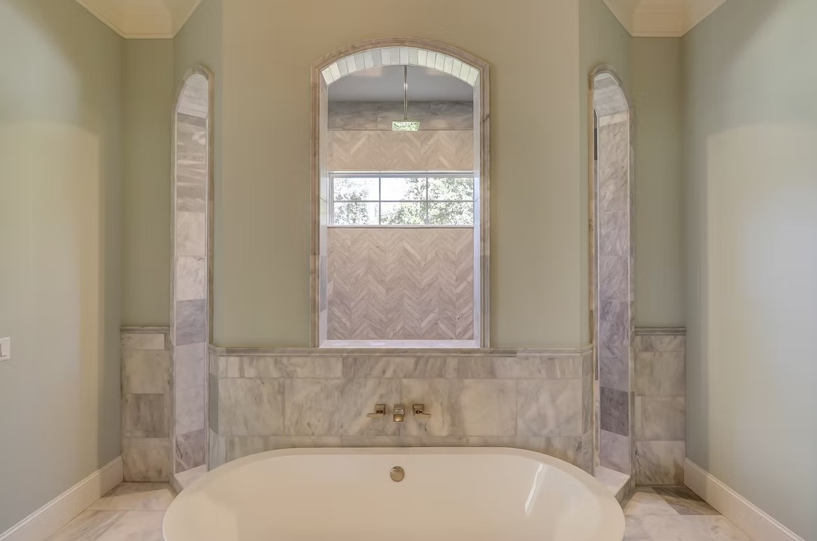 High-end bathroom corner featuring a large walk-in glass shower, premium marble tile walls, and a matching built-in stone bench.