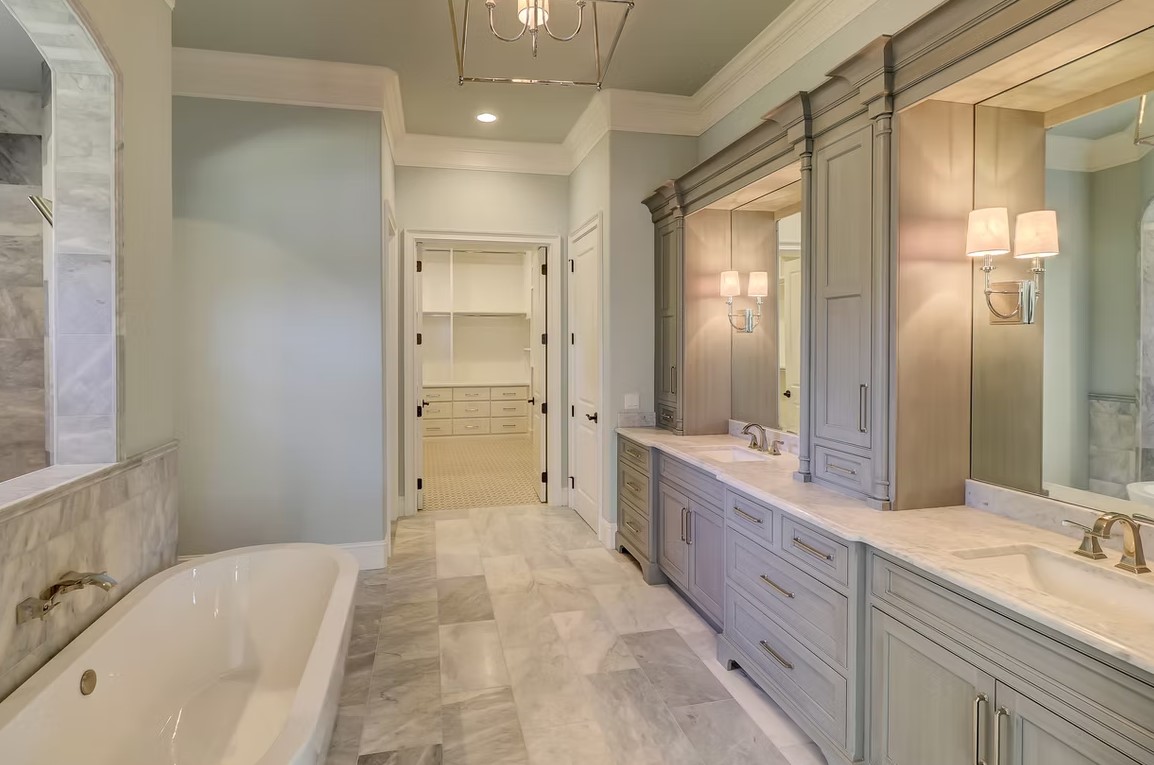 Classic luxury bathroom vanity with white shaker cabinets, a marble countertop, and large framed mirrors.