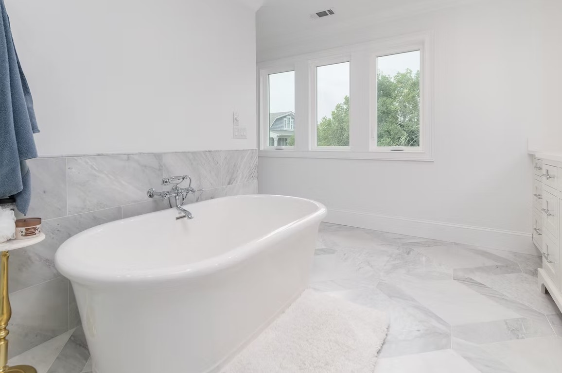 High-end bathroom vanity featuring white cabinetry, dual undermount sinks with polished silver faucets, and a marble countertop.