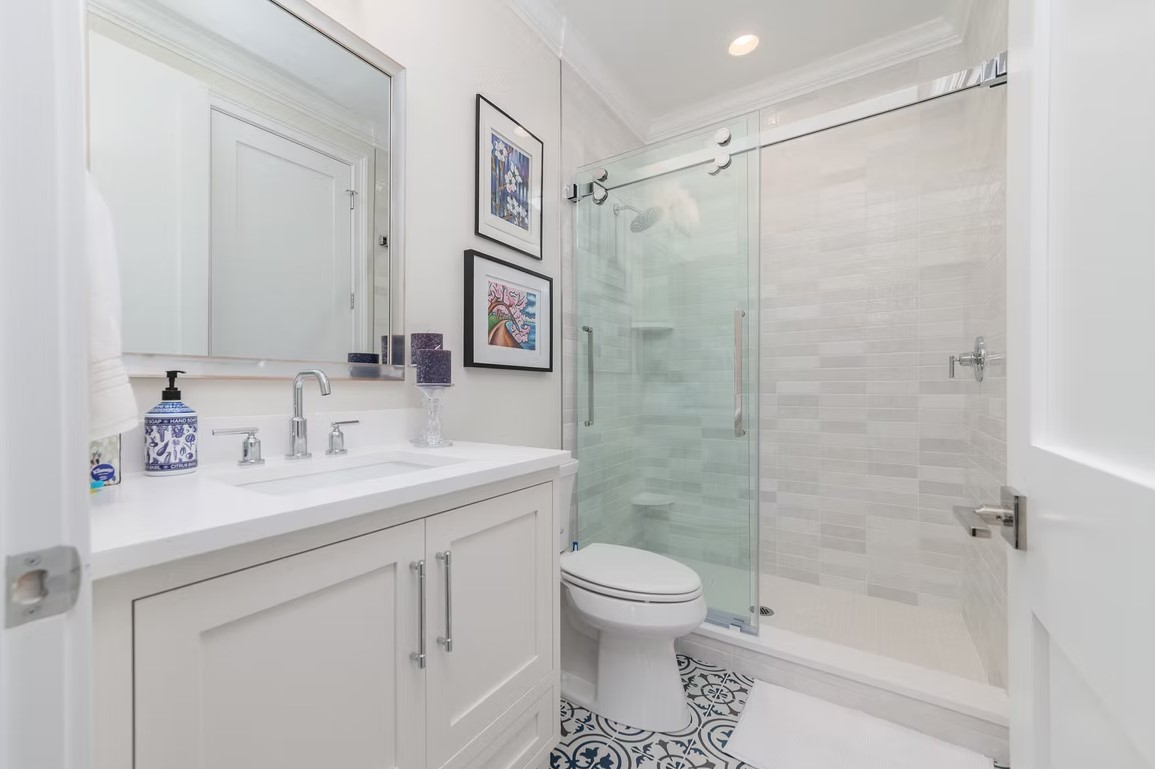 Contemporary luxury bathroom featuring a floating wood vanity, an backlit circular mirror, and textured stone wall tiles.