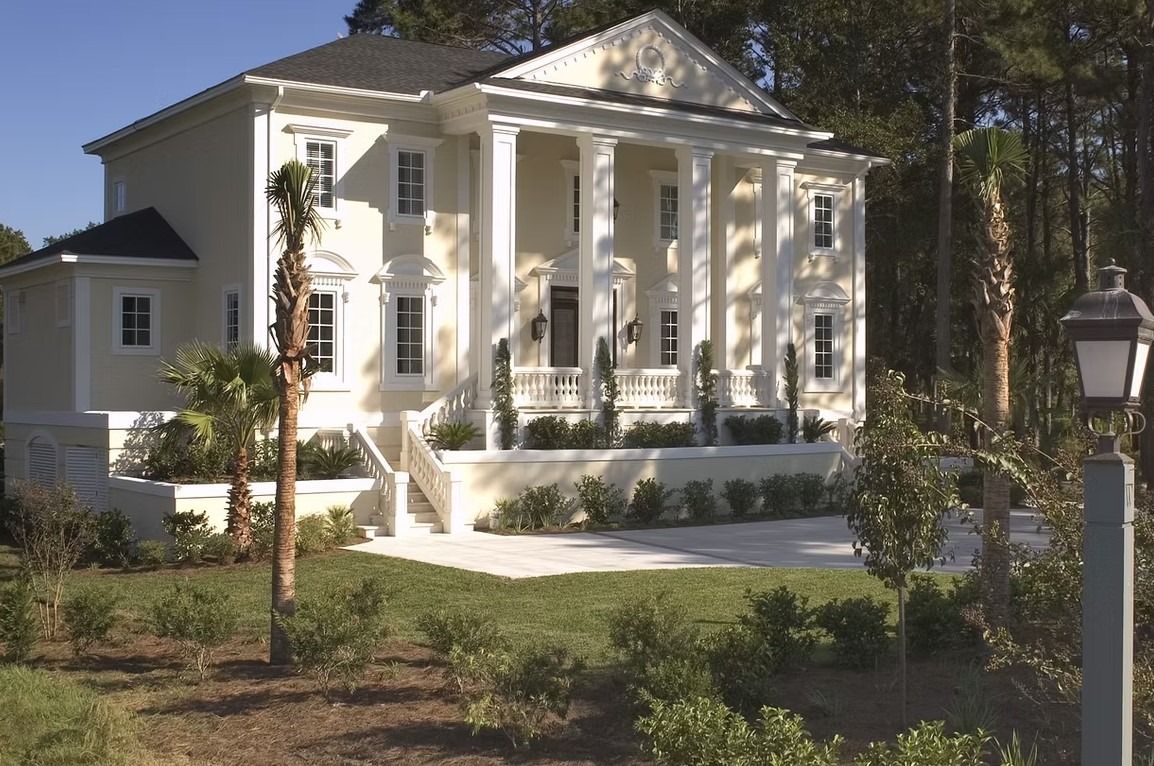 Rear view of a modern luxury estate featuring expansive floor-to-ceiling windows, white and charcoal masonry, and a manicured green lawn.