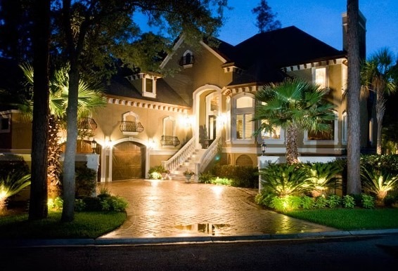 Rear view of a modern luxury estate featuring expansive floor-to-ceiling windows, white and charcoal masonry, and a manicured green lawn.