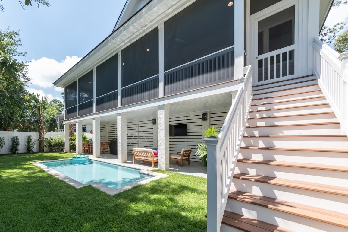 Detailed view of a modern luxury home's rear exterior featuring floor-to-ceiling glass windows, a white and charcoal facade, and a flat lawn.
