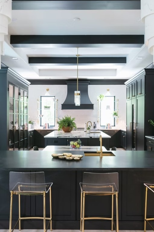 Bright modern kitchen featuring a large white marble island, gold-tone faucet fixtures, and custom floor-to-ceiling pantry storage.