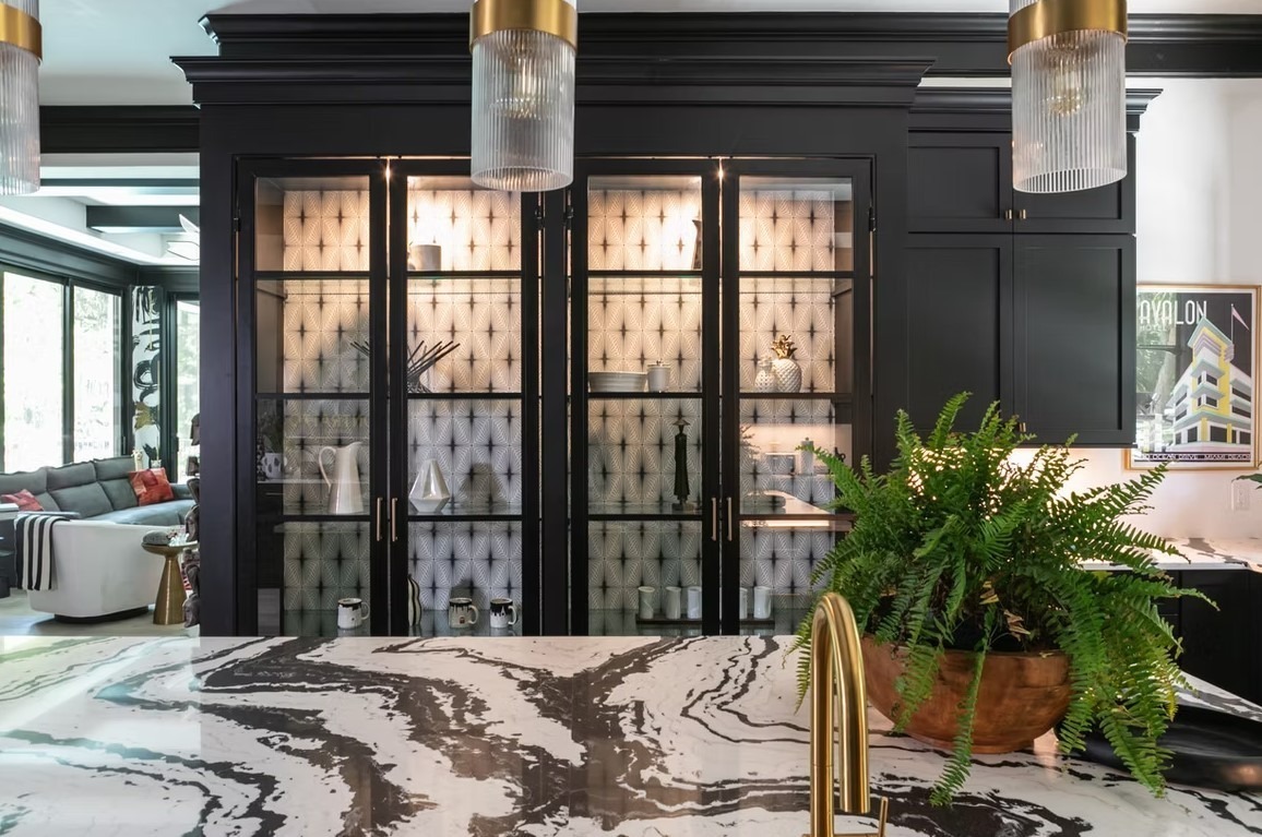 Classic luxury kitchen featuring a large central island with a white marble top, dark wood cabinetry, and elegant glass-front display cupboards.