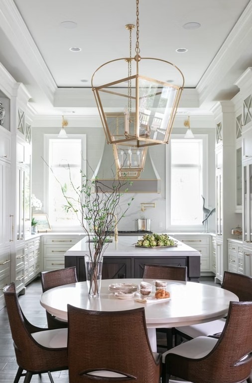Classic luxury kitchen featuring a large central island with a white marble top, dark wood cabinetry, and elegant glass-front display cupboards.