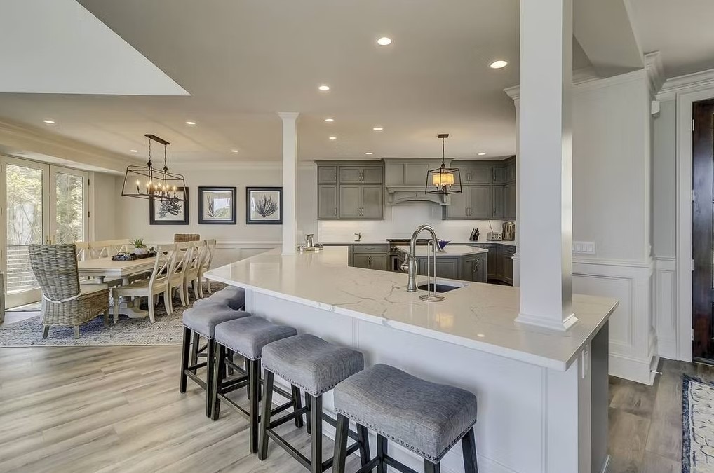 Luxury custom kitchen featuring a massive stone-topped island, bespoke cabinetry, and contemporary pendant lighting.