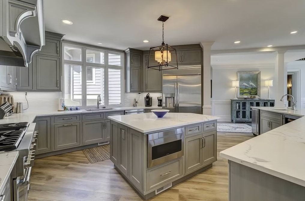 Luxury custom kitchen featuring a massive stone-topped island, bespoke cabinetry, and contemporary pendant lighting.
