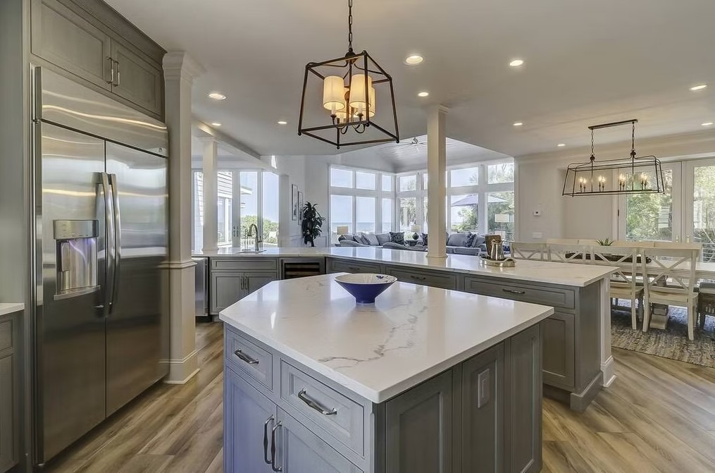 Luxury custom kitchen featuring a massive stone-topped island, bespoke cabinetry, and contemporary pendant lighting.