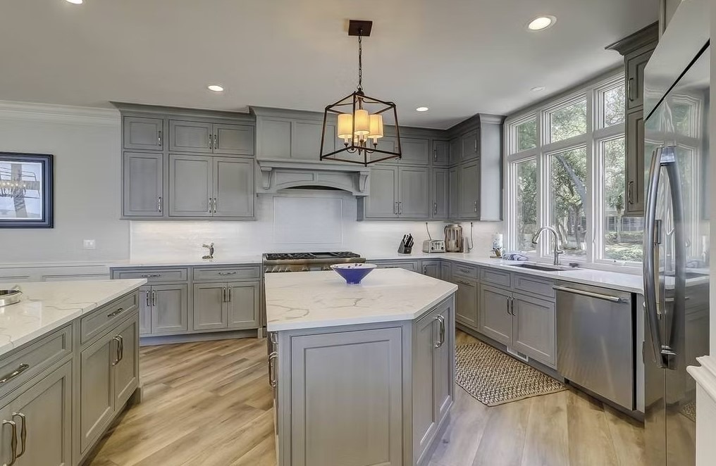 Luxury custom kitchen featuring a massive stone-topped island, bespoke cabinetry, and contemporary pendant lighting.