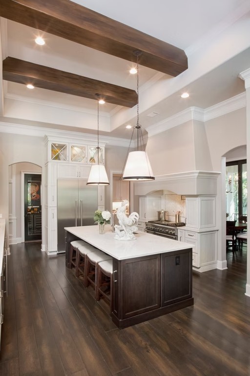 Luxury custom kitchen featuring a massive stone-topped island, bespoke cabinetry, and contemporary pendant lighting.