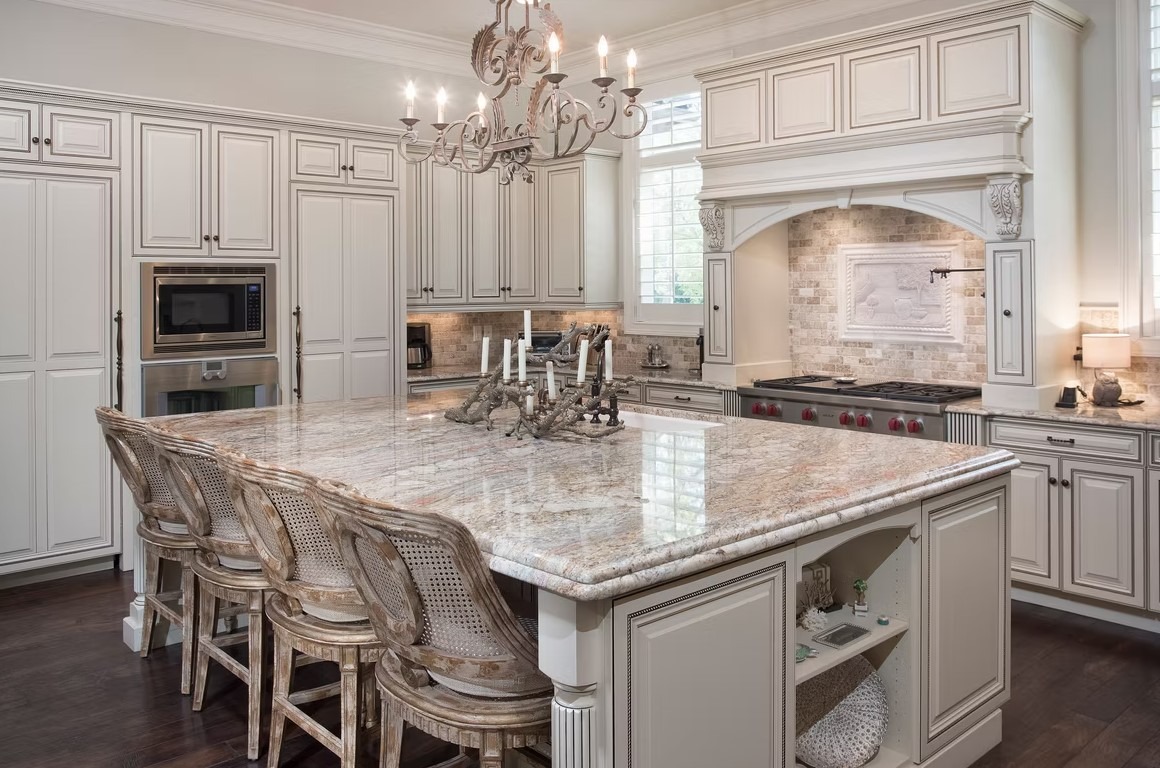Luxury custom kitchen featuring a massive stone-topped island, bespoke cabinetry, and contemporary pendant lighting.