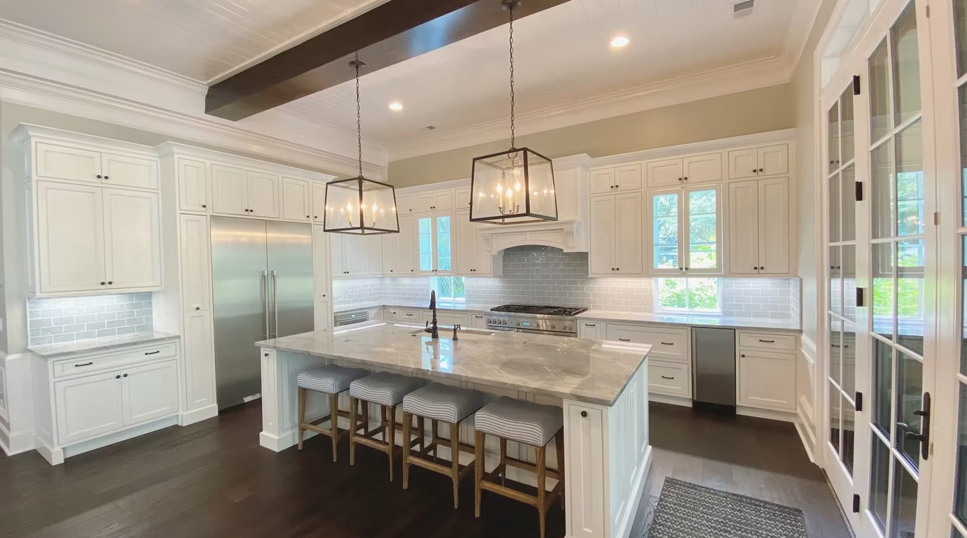 Luxury custom kitchen featuring a massive stone-topped island, bespoke cabinetry, and contemporary pendant lighting.