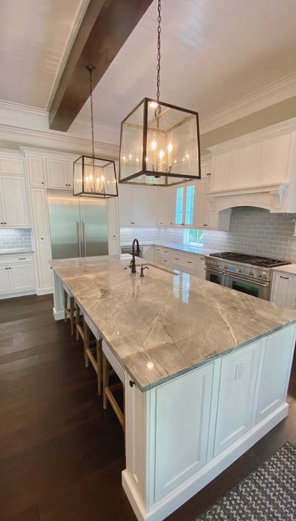 Luxury custom kitchen featuring a massive stone-topped island, bespoke cabinetry, and contemporary pendant lighting.