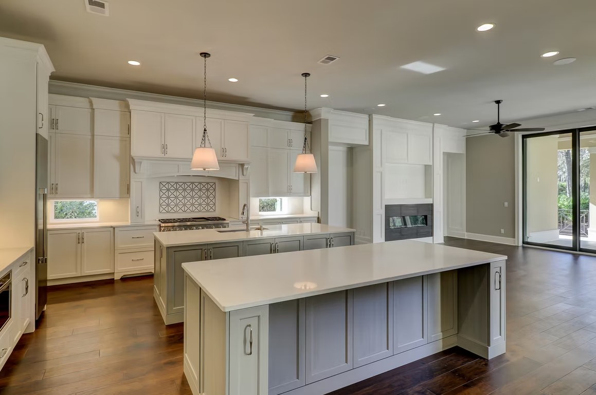 Luxury custom kitchen featuring a massive stone-topped island, bespoke cabinetry, and contemporary pendant lighting.