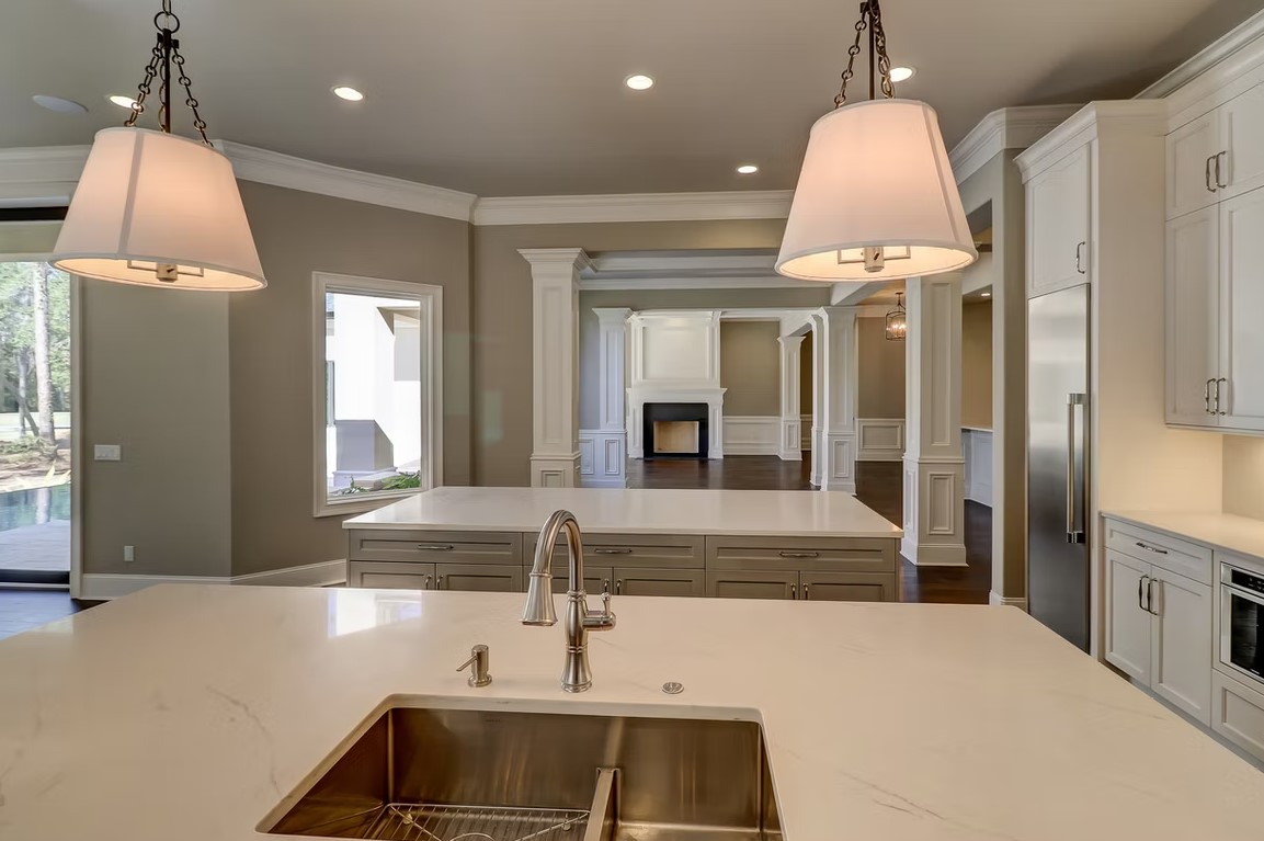 Luxury custom kitchen featuring a massive stone-topped island, bespoke cabinetry, and contemporary pendant lighting.