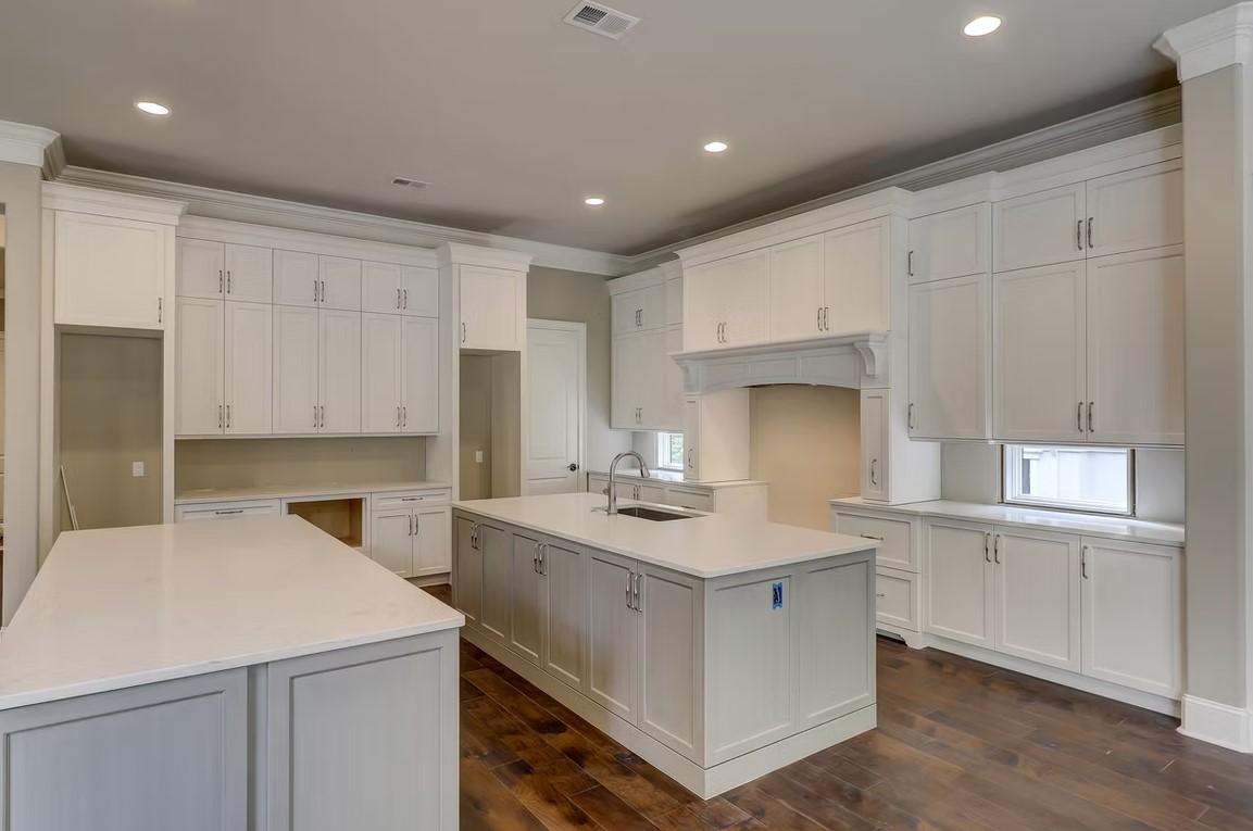 Modern luxury kitchen featuring a large stone-topped island, bespoke cabinetry, and high-end integrated appliances by Palatial Homes Design LLC.