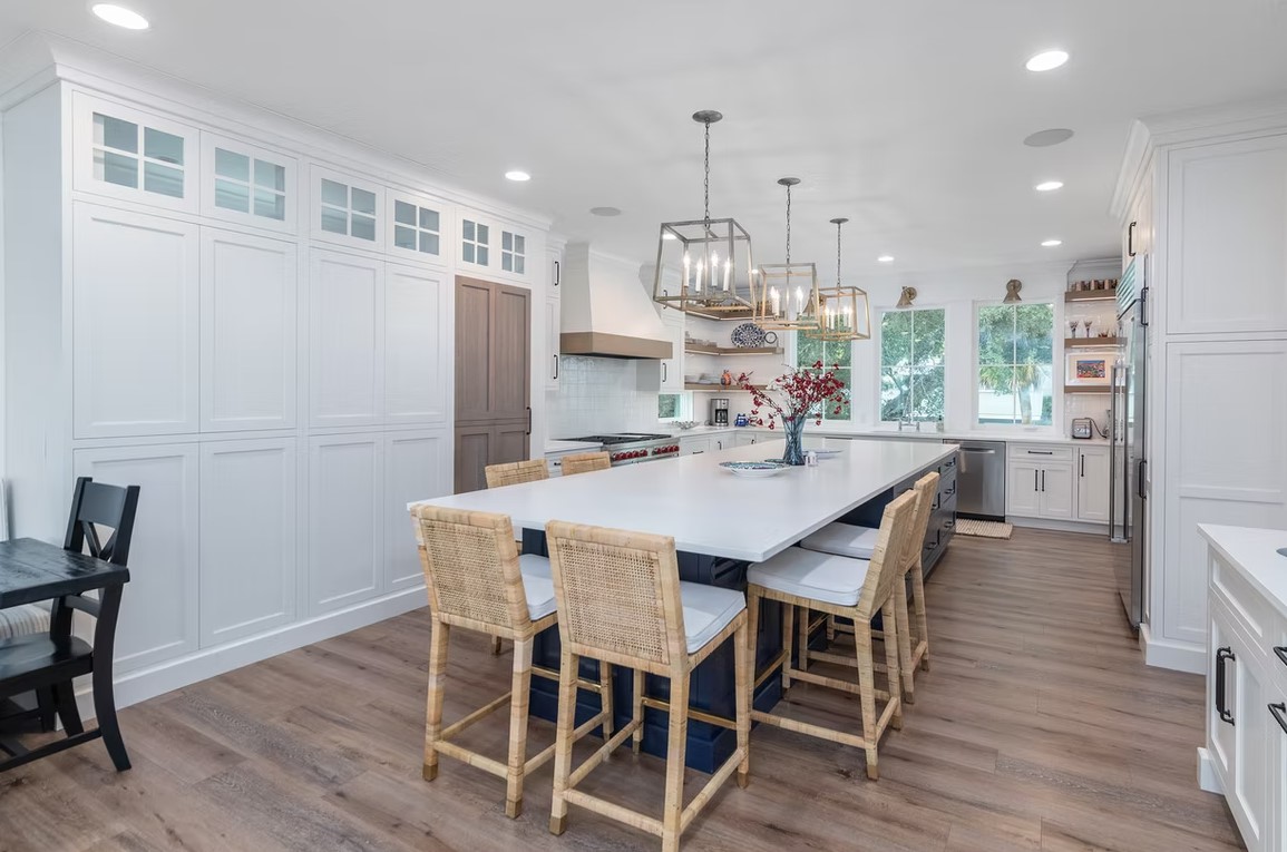 Luxury custom kitchen featuring crisp white cabinetry, a large marble-topped center island, and contemporary gold-toned pendant lighting.