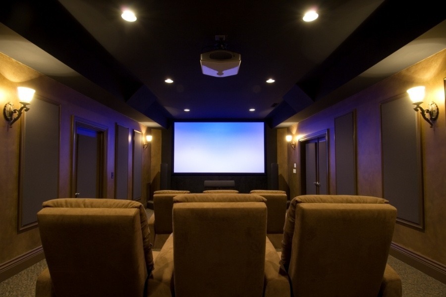 Luxury custom-designed home theater featuring plush tiered seating, high-end acoustic wall panels, and a large cinematic projection screen.